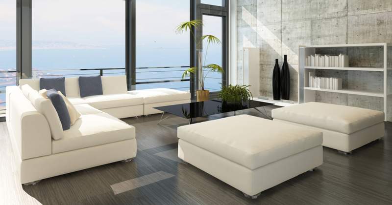 Modern living room with white furniture and a top-bottom window view of the ocean from high up